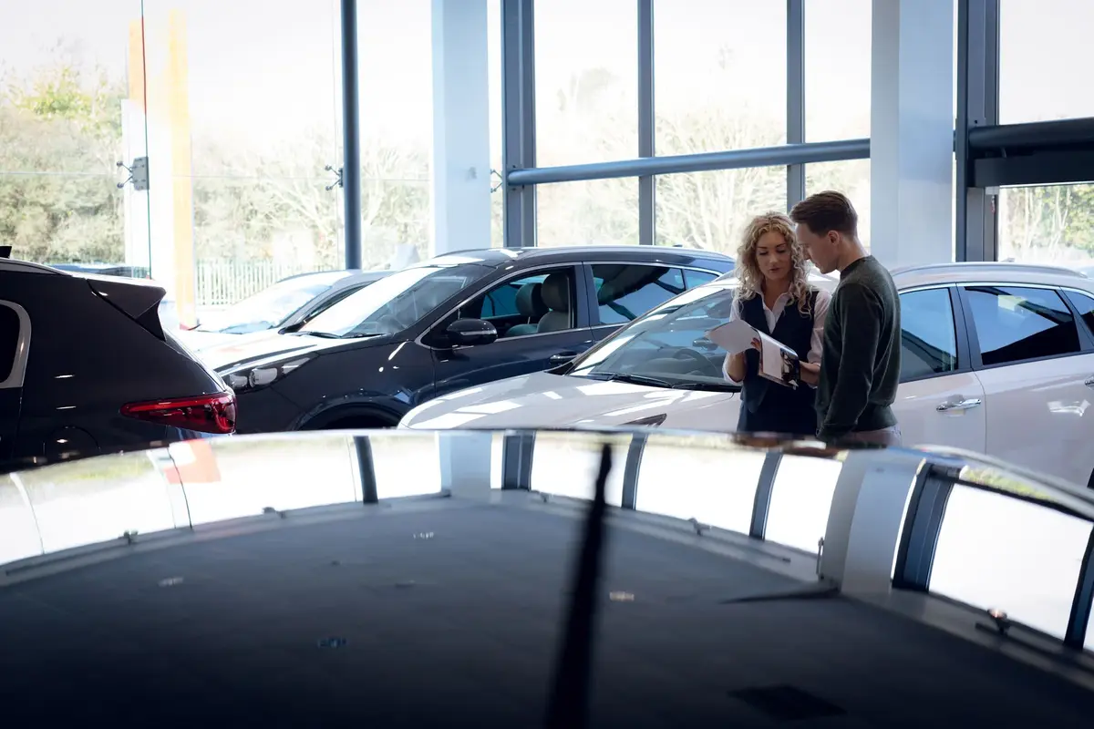 A salesperson going through paperwork with a customer in a car showroom